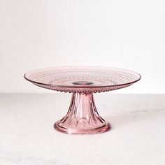 a pink glass cake plate sitting on top of a table