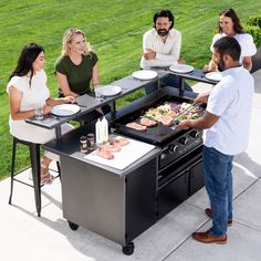 a group of people sitting around a bbq grill with food on top of it