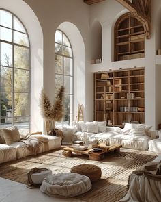 a living room filled with lots of white furniture and large arched windows next to bookshelves