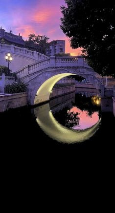 an image of a bridge that is going over the water at sunset or dawn with buildings in the background