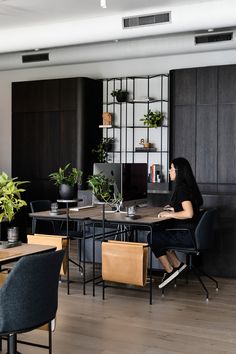 a woman is sitting at a table in the middle of a room with black chairs