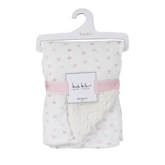 a white and pink blanket with polka dots on it, hanging from a hanger