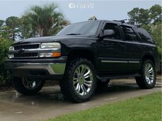 a black suv parked in front of some bushes