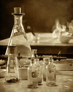 three glass bottles sitting on top of a table next to a bowl and utensils