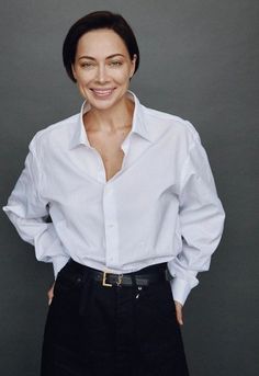 a woman in a white shirt and black pants posing for the camera with her hands on her hips