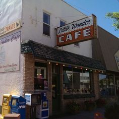 the outside of a cafe with an awning and sign on it's side