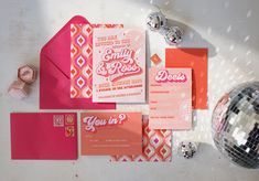 an assortment of wedding stationery and party supplies on a table with disco ball in the background