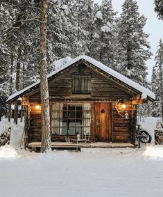 a cabin in the woods with snow on the ground