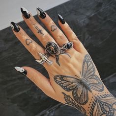 a woman's hand with tattoos and rings on it