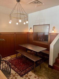 a dining room table and chairs in front of a mirror on the wall next to a stair case