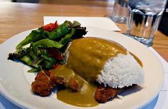 a white plate topped with rice and meat covered in gravy