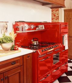 a red stove top oven sitting inside of a kitchen next to a white counter top