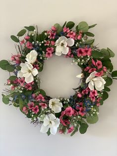 a wreath with pink, white and blue flowers hanging on the side of a wall