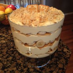 a cake that is sitting on top of a table with fruit in the back ground