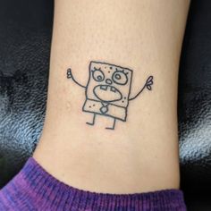 a small tattoo on the ankle of a woman's foot with a cartoon character drawn on it