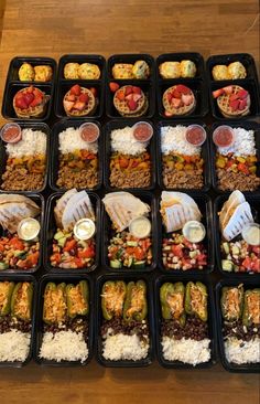 several trays filled with different types of food on top of a wooden table next to each other