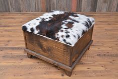 a wooden box with a cowhide cover on the top and bottom, sitting on a hard wood floor