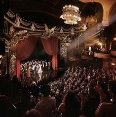 an auditorium full of people on stage with red curtains