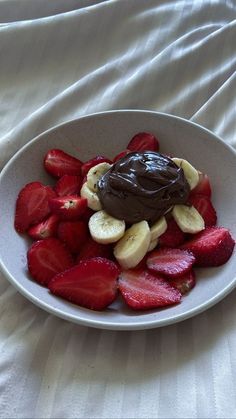 a white plate topped with sliced strawberries and chocolate covered banana slices on top of it