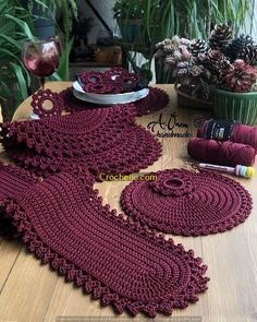 crocheted table cloths and place mats on a wooden table with potted plants in the background