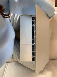 a person sitting on a couch with their laptop in front of them, holding the keyboard