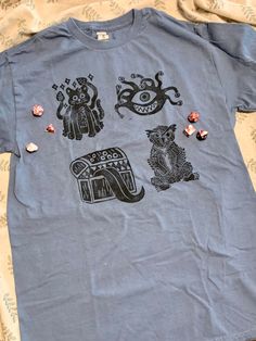 "Four block printed 5e monsters come together here: Displacer Beast, Mimic, Watcher, and Owlbear. Dice not included. Handcarved Block print design on Gildan Heavy Cotton T shirt. Printed with oil-based ink on a pre-washed t-shirt. Great for Dungeons and Dragons as well as TTRPG fans. This work includes material taken from the System Reference Document 5.1 (\"SRD 5.1\") by Wizards of the Coast LLC and available at https://dnd.wizards.com/resources/systems-reference-document. The SRD 5.1 is licensed under the Creative Commons Attribution 4.0 International License available at https://creativecommons.org/licenses/by/4.0/legalcode." Merch Concept, Displacer Beast, Stamp Shirt, 5e Monsters, Block Print Shirt, Unknown Creatures, Dnd Shirts, Shirt Illustration, Monster Mash