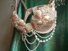 there is a purse made out of shells and pearls on the green fabric with beads hanging from it