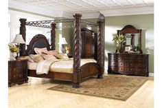 a bedroom with a canopy bed, dresser and night stand in it's center