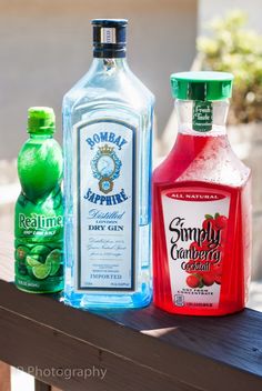 three bottles of alcohol sitting on top of a wooden table