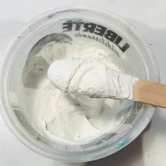 a wooden spoon is in a container of white powdered food that contains liberte