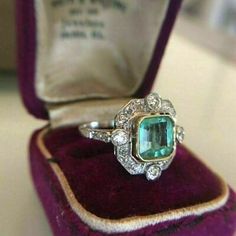 an emerald and diamond ring in a velvet box