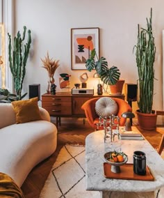 a living room filled with furniture and potted plants on top of a wooden table