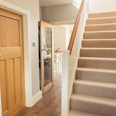 a staircase leading up to a dining room and living room with wooden doors on both sides