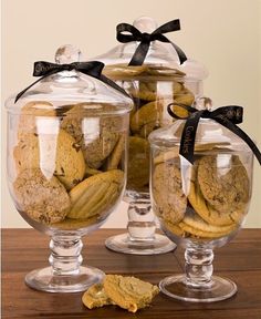 two clear glass containers filled with cookies on top of a wooden table