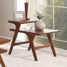 a wooden table with a vase on top of it next to a window sill