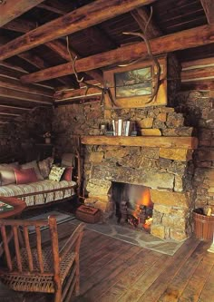 a rustic living room with wood floors and stone fireplace