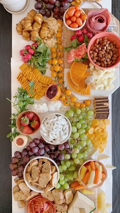 an assortment of cheeses, fruits and crackers on a platter