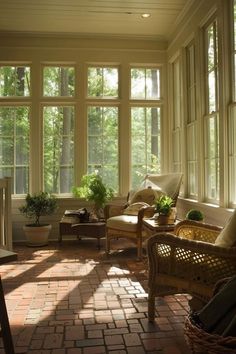 the sun shines through two large windows into a room with brick flooring and wicker furniture