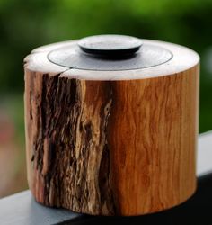 a wooden object sitting on top of a table next to a window sill with trees in the background