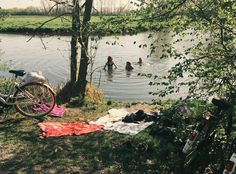 there are people swimming in the water at this campsite with bikes and blankets on the ground