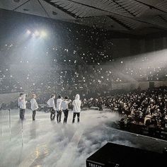 a group of men standing on top of a stage in front of a crowd at a concert