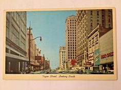 an old postcard with buildings and cars on the street