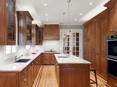 a large kitchen with wooden cabinets and white counter tops, along with an oven in the center