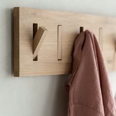 a wooden coat rack with hooks and clothes hanging from it's sides on a wall