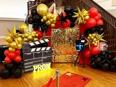 some black and gold balloons are on the ground near a red carpet with a golden star