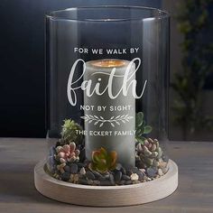 a glass candle holder with rocks and succulents in it that says, for we walk by faith not by sight