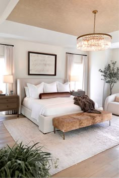 a bed room with a neatly made bed and a chandelier hanging from the ceiling