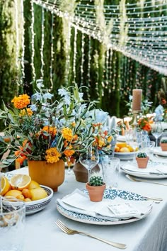 an outdoor table set with plates and flowers