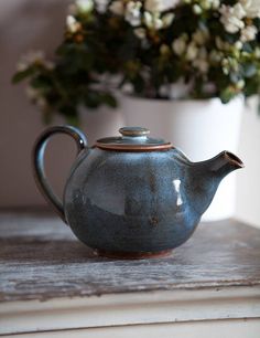 a teapot sitting on top of a table next to a potted plant