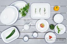 the table is set with white dishes and vegetables